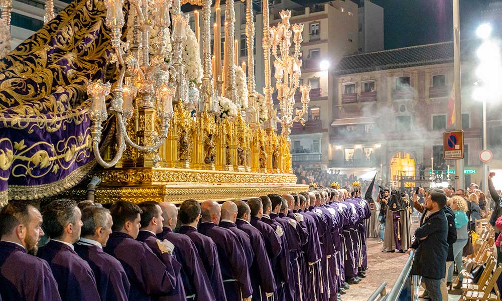 Men carrying a traditional throne during Semana Santa night procession in Malaga, reflecting the city's rich cultural heritage in March.